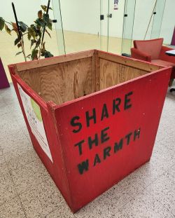 A large wooden bin with "Share the Warmth" on the side.